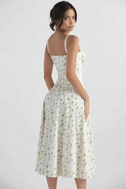 White Floral Linsay - Woman wearing a floral sweetheart midi dress with wide straps, a fitted bodice, and a flowing A-line skirt with a front slit.