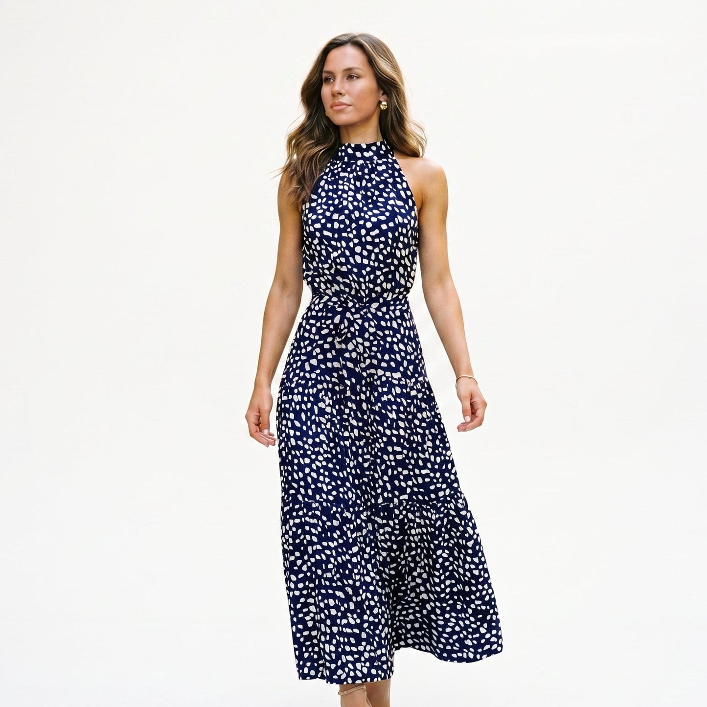 Navy Blue - Woman wearing a spotted halter neck maxi dress with a tie waist and tiered skirt.