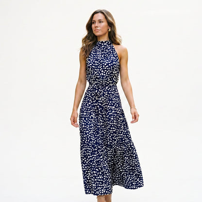 Navy Blue - Woman wearing a spotted halter neck maxi dress with a tie waist and tiered skirt.