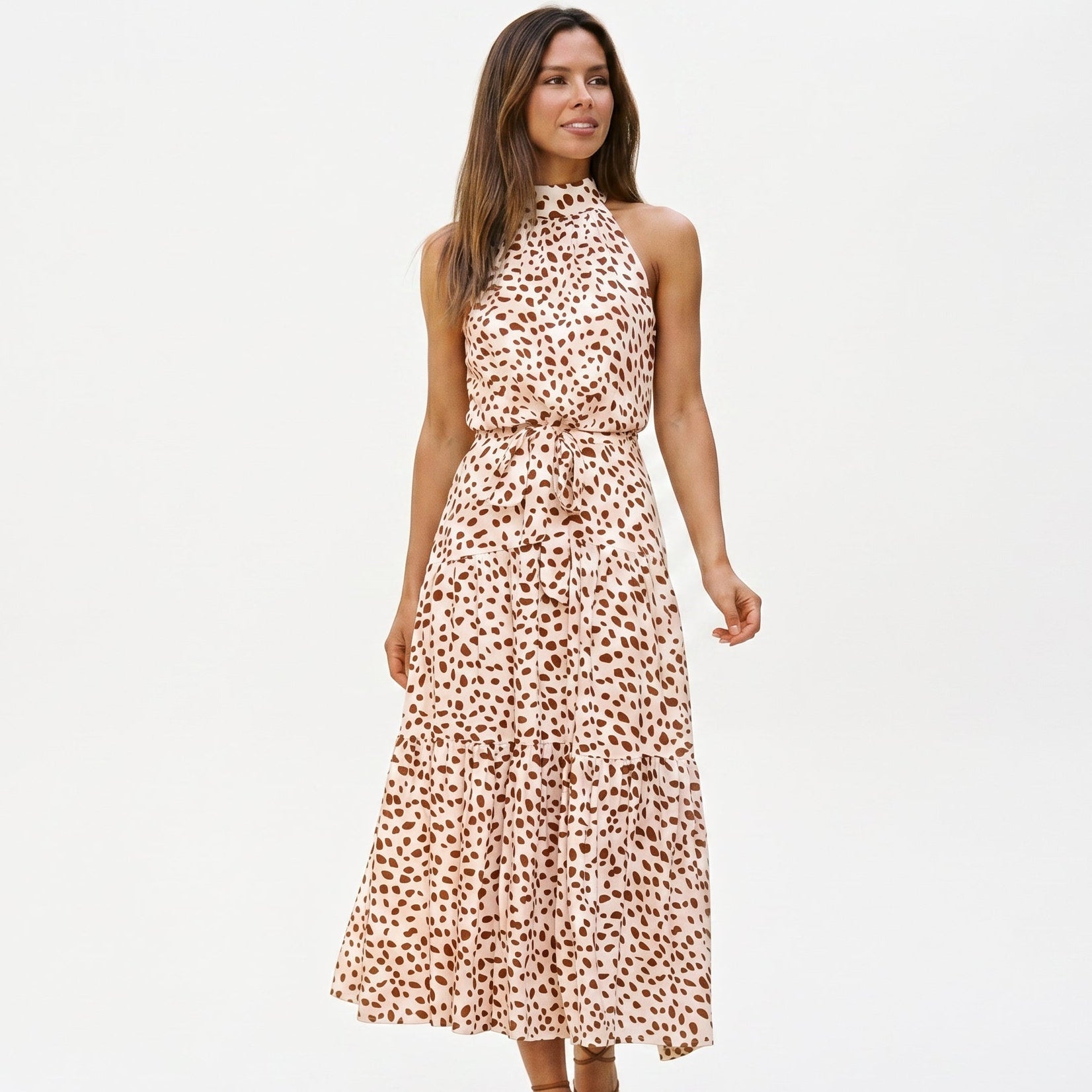 White - Woman wearing a spotted halter neck maxi dress with a tie waist and tiered skirt.