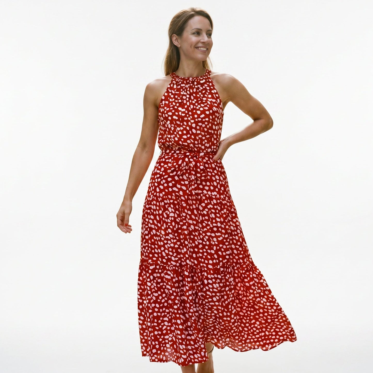 Red - Woman wearing a spotted halter neck maxi dress with a tie waist and tiered skirt.