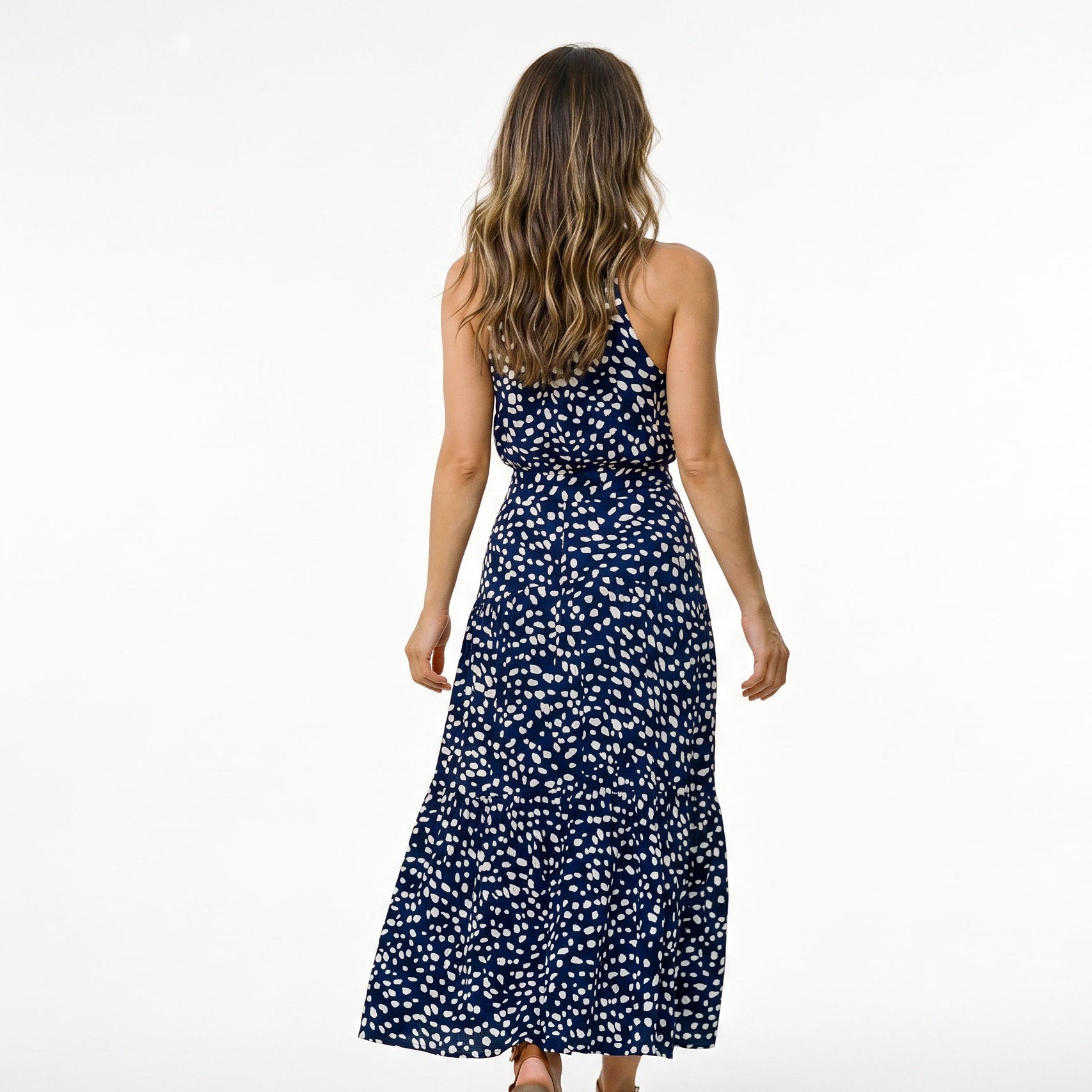 Red - Woman wearing a spotted halter neck maxi dress with a tie waist and tiered skirt.
