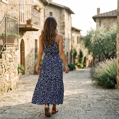Red - Woman wearing a spotted halter neck maxi dress with a tie waist and tiered skirt.