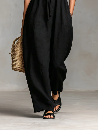 Light Pink - Model wearing a strapless wide-leg jumpsuit with a ruched bodice, front tie detail, and side pockets, holding a woven bag.